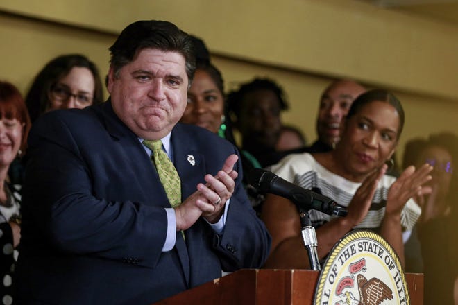 Gov. J. B. Pritzker takes in the applause before signing a bill that legalizes adult-use cannabis in the state of Illinois at Sankofa Cultural Arts and Business Center in Chicago. Illinois becomes the 11th to legalize the adult-use of recreational marijuana. (AP Photo/Amr Alfiky)