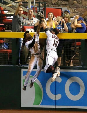 Arizona Diamondbacks center fielder Jarrod Dyson, left, makes a catch taking a home run away from Los Angeles Dodgers' Joc Pederson as Dyson collides with Diamondbacks right fielder Tim Locastro (16) during the seventh inning of a baseball game Wednesday, June 26, 2019, in Phoenix. (AP Photo/Ross D. Franklin)