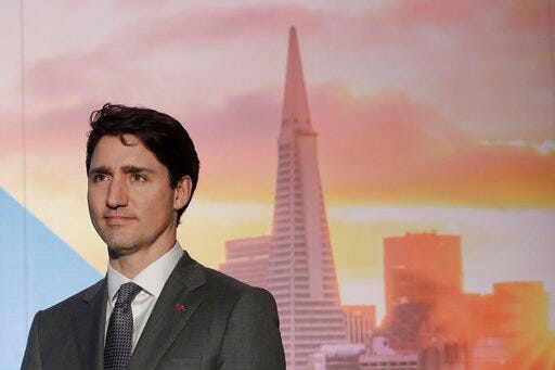 FILE - In this Feb. 8, 2018, photo, with an image of the San Fransisco skyline in the background, Canada's Prime Minister Justin Trudeau waits to speak at the AppDirect office in San Francisco. California picked up an important partner its long-running dispute with the Trump administration over vehicle emissions and fuel economy by announcing a deal with Canada to work on pollution reductions. (AP Photo/Jeff Chiu, File)