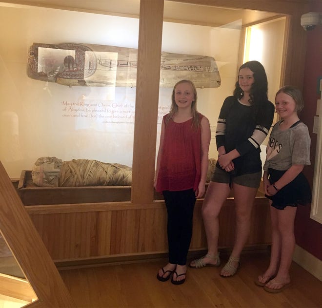 Cazenovia Library patrons, from left, Sophia Abernathy, Claire Hunt and Tabitha Abernathy check out the mummy Hen June 20 in the library's ongoing Egyptian exhibit. [COURTESY ELISHA DAVIES]