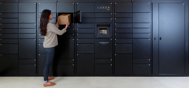 This photo provided by Luxer One shows a woman removing a package from one of Luxer's access lockers in San Francisco, Calif. Luxer One provides secure lockers in buildings in the United States and Canada that can be accessed by both delivery companies and residents. (Luxer One via AP)