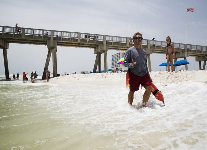 Bay County lifeguard Dustin Marsden walks Panama City Beach near the MB Miller County Pier, warning swimmers about the riptide near the shore on Tuesday, June 25 2019. [JOSHUA BOUCHER/THE NEWS HERALD]