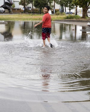 Alejandro Canseco, 8, plays in a puddle following a rainstorm in downtown Panama City on June 6, 2019. "I like it because it's cool and fresh," he said. [JOSHUA BOUCHER/THE NEWS HERALD]