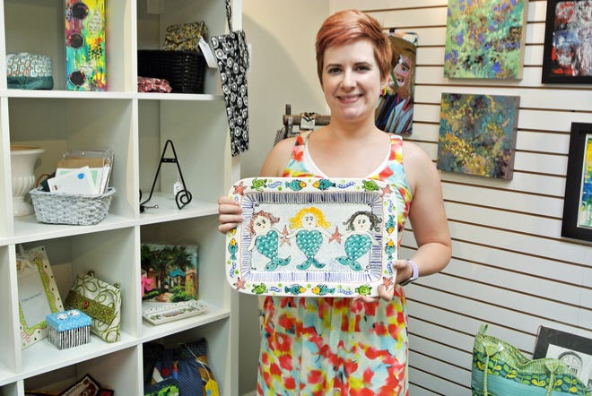 The Cultural Center at Ponte Vedra Beach exhibition and communications manager Sara M. Bass holds a hand-painted tray made by ceramics artist Caroline Forbis. It is one of many original works of art for sale at the Center's The Market. which recently opened. [JACKIE ROONEY/FOR SHORELINES]