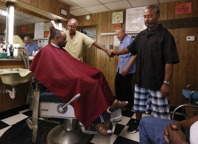 Paul Locke, center, watches Bob Dillard cut customer Grady Harris' hair while Dillard shakes hands with fellow barber Richard Blue, who works down the street and stopped by to wish Locke and Dillard a happy retirement. The pair closed their shop Friday. [Eric Albrecht/Dispatch]