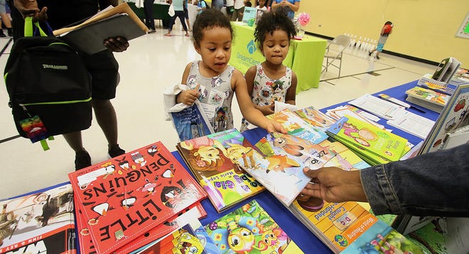Sisters Amara Miller, left, and Abriell Miller pick out free books during a past Highland Community Back-to-School Bash. The free books table was set up by The Partnership for Children of Lincoln and Gaston Counties. [MIKE HENSDILL/THE GASTON GAZETTE]