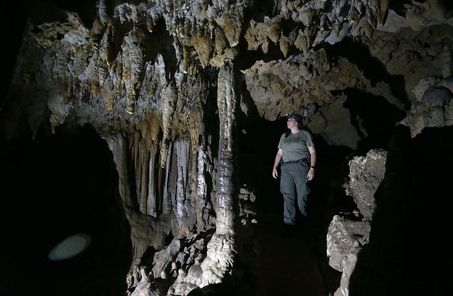 Park Services Specialist Amanda Glover looks over formations inside of a cavern on Thursday at the Florida Caverns State Park. A portion of the park is set to reopen on Monday. [PATTI BLAKE/THE NEWS HERALD]