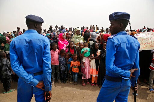 Sudanese policemen stand guard, as supporters of Gen. Mohammed Hamdan Dagalo, the deputy head of the military council, better known as Hemedti, attend a military-backed rally, in Mayo district, south of Khartoum, Sudan, Saturday, June 29, 2019. Sudan's ruling generals say they have accepted a joint proposal from the African Union and Ethiopia to work toward a transitional government. (AP Photo/Hussein Malla)
