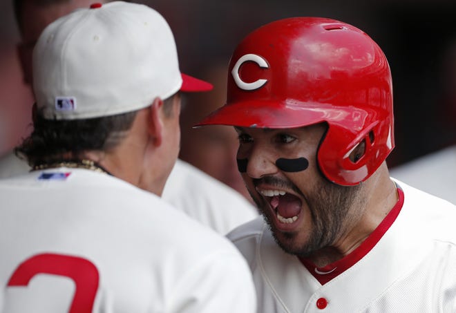 The Cincinnati Reds' Eugenio Suarez, right, reacts in the dugout following a three-run home run off Chicago Cubs starting pitcher Jon Lester during the first inning Sunday in Cincinnati. [GARY LANDERS/THE ASSOCIATED PRESS]