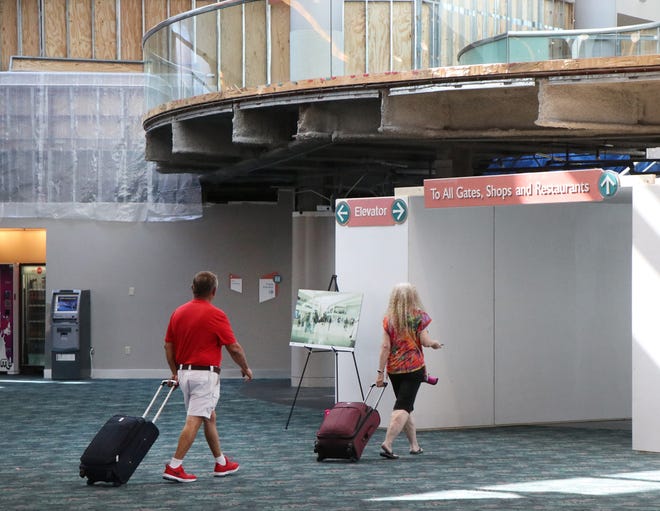 Travelers on their way to the gates at Daytona Beach International Airport, Tuesday June 25, 2019 walk through a protective tunnel under the balcony, where work has started to remove the balcony overlooking the main entrence and ticket counters.  [News-Journal/David Tucker]