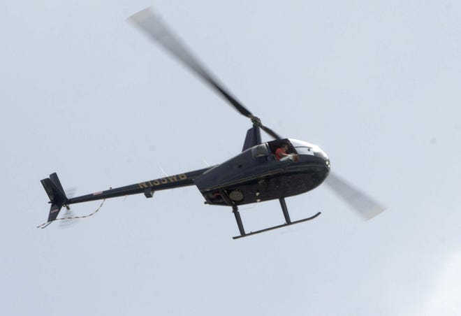 A helicopter from a Destin helicopter company flies over Henderson Beach State park recently. Destin's helicopter companies have altered their routes and now are flying only eastward, away from Destin. [NICK TOMECEK/DAILY NEWS]