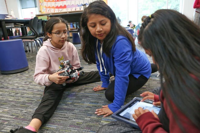 Alexis Silva-Figueroa (left) holds a Gigabot as Laura Vasquez-Vasquez and Lupita Silva-Hernandez work on coding during a Coder in Residence class at River Road Elementary School in Eugene. [Kelly Lyon/The Register-Guard]