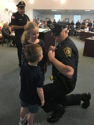 Sgt. Thomas Mori's children help pin his badge after he's sworn in Tuesday night. [Wicked Local photo/Kathryn Gallerani]