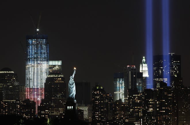 In this Sept. 10, 2011 file photo, the "Tribute in Light" shines above lower Manhattan, the Statue of Liberty, and One World Trade Center. [AP PHOTO/MARK LENNIHAN/FILE]