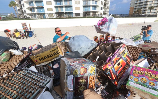 CFB Outdoors Beach Maintence crews carry arm fulls of fireworks trash in Daytona Beach Shores Friday morning. The Fifth of July is traditionally peak beach garage day. [News-Journal/David Tucker]
