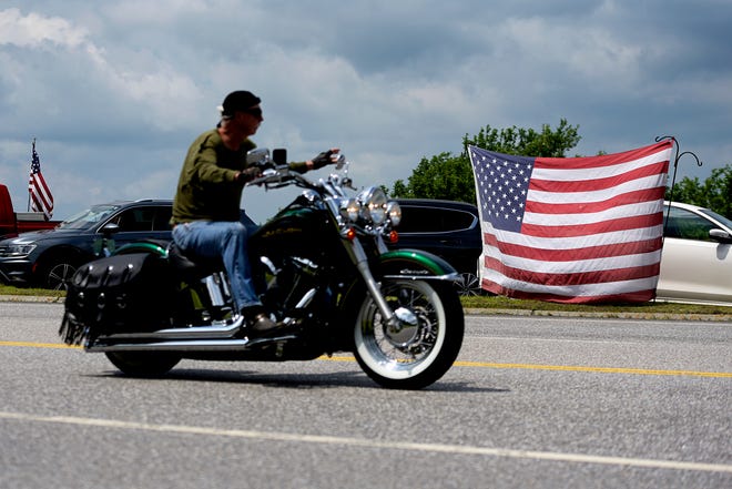 A motorcyclist passes an American flag on the route for the Ride for the Fallen 7 in near Randolph, N.H., on Saturday, July 6, 2019. Thousands of motorcyclists traveled through parts of New Hampshire as a tribute to the seven bikers killed in a collision with a pickup truck last month. (Paul Hayes/Caledonian-Record via AP)