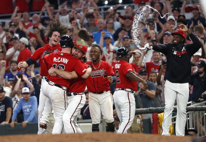 The Braves' Brian McCann (16) is mobbed by his teammates after driving in the winning run with a base hit in the ninth inning against the Miami Marlins early Saturday in Atlanta. The Braves won 1-0. [JOHN BAZEMORE/THE ASSOCIATED PRESS]