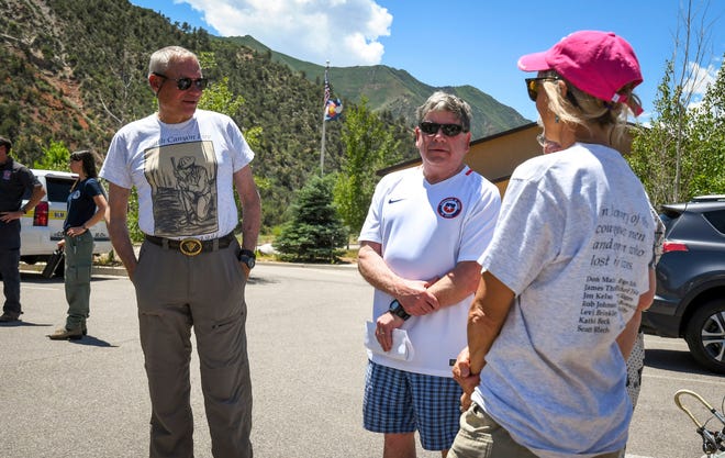 Family members of Roger Ross speak with New Castle, Colo., Mayor Art Riddile, second right, at the Storm King Fire press conference on Saturday, July 6, 2019, near Glenwood Springs, Colo., marking 25 years since the lives of 14 Wildland firefighters were lost on Storm King Mountain which looms in the background. (Chelsea Self/Glenwood Springs Post Independent via AP)