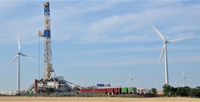 A rig drills for oil in Oklahoma's STACK play in northwest Oklahoma on land near an operating wind farm. The Oklahoma Corporation Commission regulates both industries, and an ongoing upgrade of its data systems is intended to both make it easier for regulated companies to do business with the agency and to make it easier for the public to obtain information about the agency's regulatory activities. [OKLAHOMAN ARCHIVES]