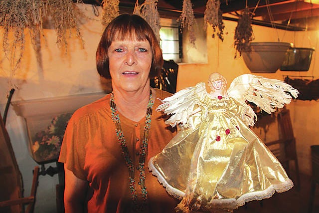 Drummond Home curator Beverly Whitcomb displays a Christmas angel damaged by spring flooding. Four feet of water collected in the Drummond Home basement, Whitcomb said. Robert Smith/Journal-Capital