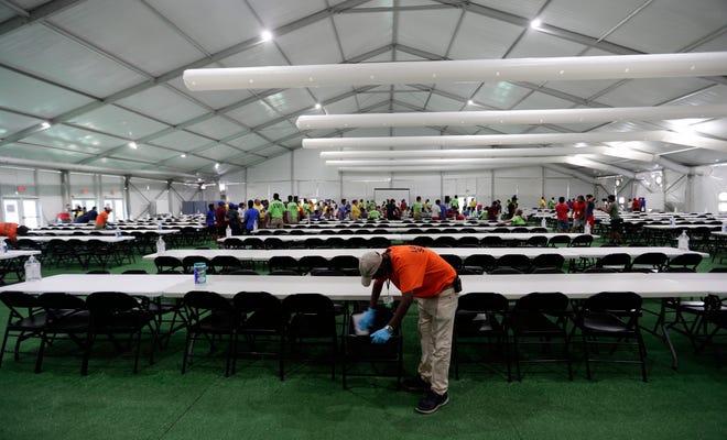 In this July 9, 2019, photo, a staff member cleans in a dinning hall at the U.S. government's newest holding center for migrant children in Carrizo Springs, Texas. The government said the holding center will give it much-needed capacity to take in more children from the Border Patrol. (AP Photo/Eric Gay)