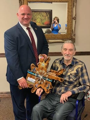 Richard Shmeltz of High Springs, seated, delivers a carved clock to Walton County Sheriff Mike Atkinson on Tuesday. [CONTRIBUTED PHOTO]