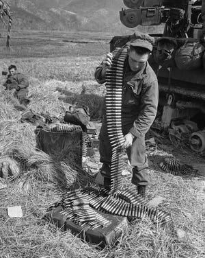 Cpl. Thomas L. Shillinger, of Turtle Creek, Pa., stacks a belt of 50-caliber ammunition on the western front in South Korea on March 10, 1951, after helping his gun crew fire at Chinese positions all morning.  [AP File Photo]
