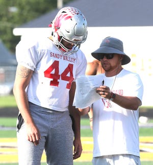 Sandy Valley's Bryce Kelly speaks with East assistant coach Brian Gamble during a workout at Hoover in preparation for the Canton Repository East-West All-Star Football Game. Gamble is the head football coach at Sandy Valley.