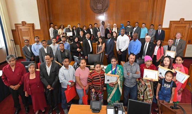 Forty-two new U.S. citizens who came from 14 countries are shown following a citizenship and naturalization ceremony at U.S. District Court in Erie on Friday. Presiding over the ceremony (shown at center) are, from left: U.S. Magistrate Judge Richard Lanzillo, U.S. District Judge Susan Paradise Baxter and Erie County Judge Stephanie Domitrovich. [CHRISTOPHER MILLETTE/ERIE TIMES-NEWS]