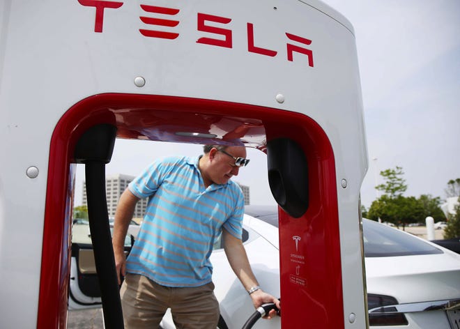 Bill Borgeson charges his Tesla Model S in Rolling Meadows, Ill., on June 3. Illinois electric vehicle owners will have to pay $248 in annual registration fees next year - $100 more than what owners of gas-burning cars will pay. [Stacey Wescott/Chicago Tribune/TNS]