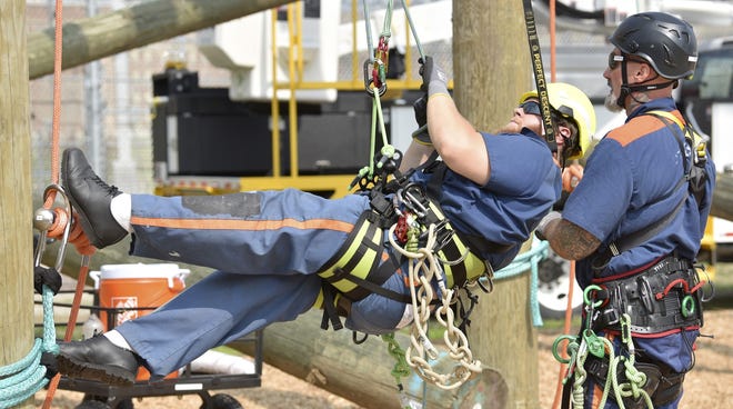 Student inmate Ted O'Hearn, left, makes sure his ropes are secure with the help of fellow student inmate Jeffrey Gunnells, right, during the demonstration for tree trimming Tuesday, July 9, 2019, in Jackson, Mich. DTE Energy and Michigan´s prison system have launched a tree-trimming program that aims to fill open jobs and find full-time employment for released inmates. State, utility and union officials announced the program Tuesday at the Parnall Correctional Facility in Jackson. (Todd McInturf/Detroit News via AP)