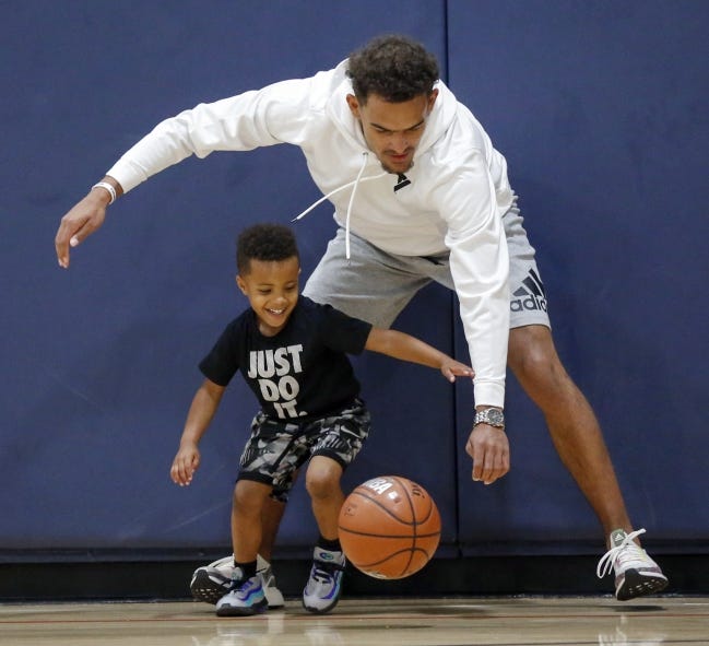 Atlanta guard Trae Young dribbles the ball with Drayton Berry, 4, during his youth basketball camp at the Santa Fe Family Life Center in Oklahoma City on Saturday. [Nate Billings/The Oklahoman]