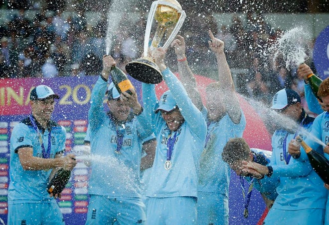 England's captain Eoin Morgan is sprayed with champagne as he raises the trophy after winning the Cricket World Cup final match between England and New Zealand at Lord's cricket ground in London, Sunday, July 14, 2019. England won after a super over after the scores ended tied after 50 overs each. (AP Photo/Matt Dunham)