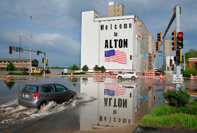 A vehicle drives through Mississippi River flood water in downtown Alton on May 6. Flooding from the Mississippi River closed streets in downtown, forced the closure of Argosy Casino and flooded the basements of several businesses. The Mississippi River is expected to crest at 34.8 feet later on Monday, almost 14 feet above flood stage. The red painted line beneath the American flag on the grain silos denotes the height of flood water in 1993. (David Carson/St. Louis Post-Dispatch via AP)