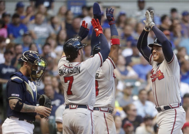 Atlanta Braves' Freddie Freeman is congratulated by Ronald Acuna Jr. (13) and Freddie Freeman (5) after hitting a three-run home run during the fourth inning of a baseball game against the Milwaukee Brewers Monday. (AP Photo/Morry Gash)