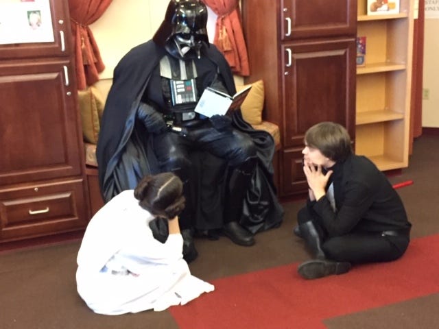 Darth Vader shows a lighter side, reading to his children, "Princess Leia" and "Luke Skywalker," last year at the Ellwood City Area Public Library. [Submitted]