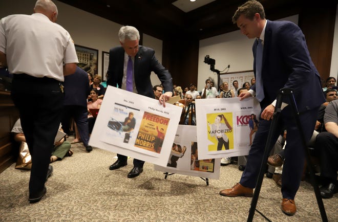 Sen. John Keenan and an aide picked up side-by-side comparisons of vintage cigarette ads and modern e-cig marketing materials. [Photo: Sam Doran/SHNS]