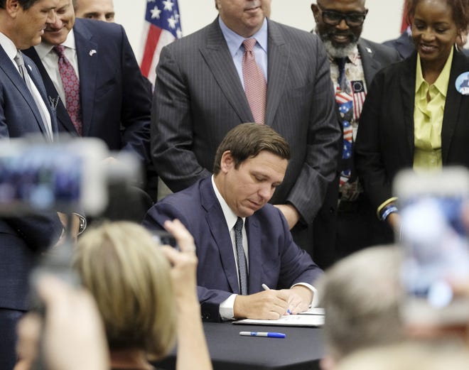 Gov. Ron DeSantis signs the Sanctuary City bill on June 14 at the Okaloosa County Commission Chambers in Shalimar. The bill requires all law enforcement agencies in Florida to cooperate with federal immigration authorities. [Michael Snyder/Northwest Florida Daily News]
