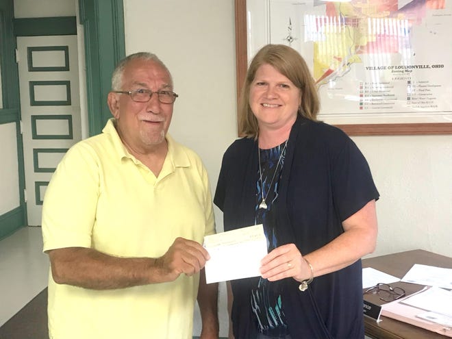 Don Riffle, first vice commander of Loudonville American Legion Post 257, presents a check for $18,604.76 to village council member Cathy Lance, another contribution toward construction of the village maintenance building. The donation was made at the council meeting Monday, July 15.