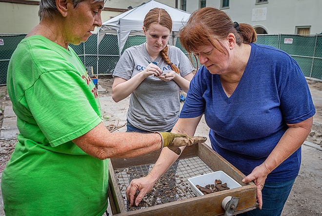 Volunteer archaeologists Pat Balanzategui, Melody Andersson-Deporris and Laura Anderson help search through dirt taken from an archeological dig on Aviles Street in St. Augustine on Tuesday. [PETER WILLOTT/THE RECORD]