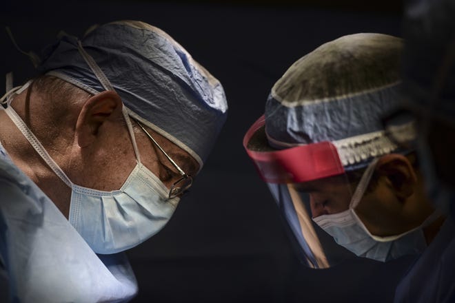 A surgical oncologist works hand in hand with a resident during a thyroid surgery. [AP Photo/Carlos Giusti/ File]