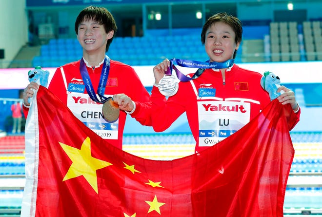 Gold medalist China's Chen Yuxi, left, stands with compatriot and silver medalist Lu Wei, as they pose for photgraphers after the women's 10m platform diving final at the World Swimming Championships in Gwangju, South Korea, Wednesday, July 17, 2019. (AP Photo/Lee Jin-man)