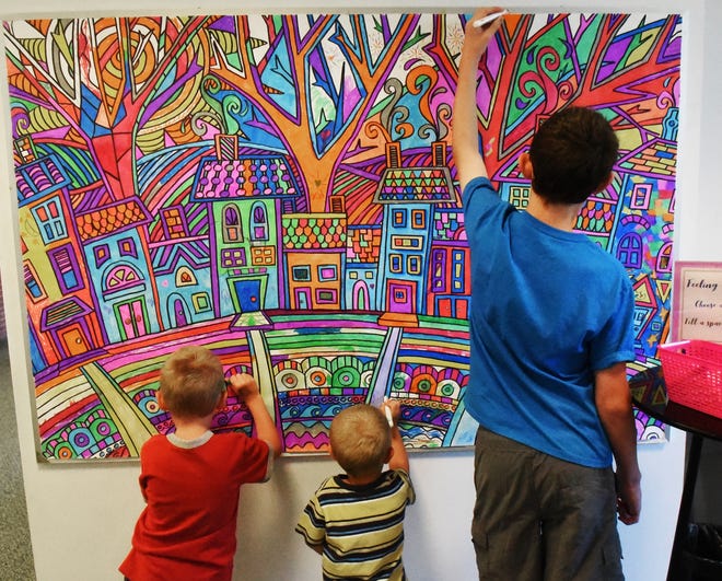 Myles Ross, 7, left, Merrick Ross, 5 and Max Ross, 13, of Rochester take a moment to color a community art project in the public library on Thursday.
[Deb Cram/Fosters.com]
