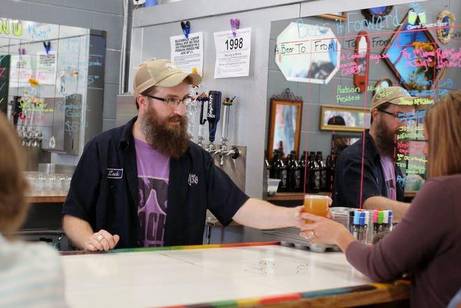 Zack Bigelow, one of three co-founders of Ramshackle Brewing Company, serves the brewery's first official customer during Wednesday's opening.