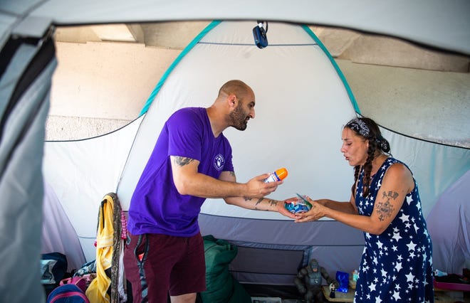 Arlene Page, a woman whose tent partially burned Wednesday after a firework was thrown at it, accepts hygiene materials and new bedding Friday from Tarik Wish, a teaching assistant at St. George's Episcopal School. [ELI IMADALI/AMERICAN-STATESMAN]