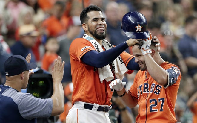 Houston Astros' Robinson Chirinos, center, ruffles Jose Altuve's hair as Altuve heads into the dugout after his home run during the third inning of the team's baseball game against the Texas Rangers on Friday at Minute Maid Park in Houston. [AP Photo/Michael Wyke]