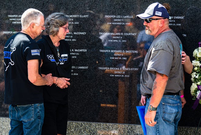 Mark and Carol Jones, left, the parents of Illinois State Police Trooper Brooke Jones-Story, and her husband Robert Story Jr., right, and sister Lindsey Jones unveil her name inscribed on the wall of the Illinois State Police Memorial Park in downtown Springfield during a ceremony on Saturday. [Justin L. Fowler/The State Journal-Register]
