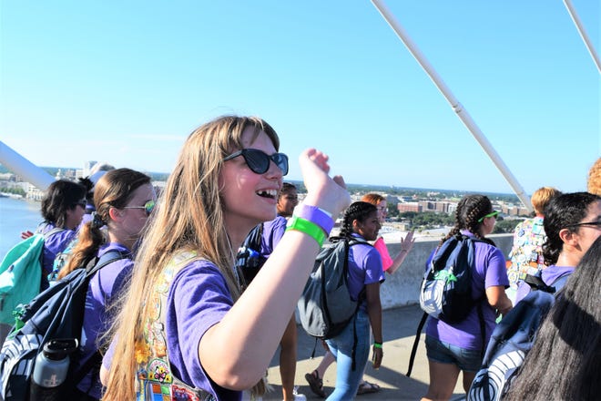 Girl Scouts wave to oncoming traffic as they walk across the Talmadge Bridge for their bridging ceremony Saturday. [Leslie Moses/for savannahnow.com]