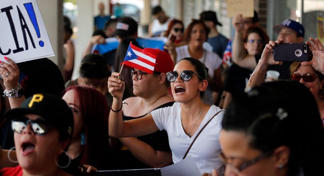 About 200-300 people from the North Texas (Dallas-Fort Worth area) Puerto Rican community gather to protest Gov. Ricardo Rossello outside the Adobo Puerto Rican Cafe in Irving, Texas, Sunday, July 21, 2019. Puerto Rico's embattled governor says he will not seek re-election but will not resign as the island's leader, though he will step down as head of his pro-statehood party. (Tom Fox/The Dallas Morning News via AP)