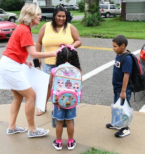 Kara Rankin, (left) assistant principal of Accelerating Innovative Minds Academy, welcomed parents and students to school Monday, including mom Erika Rios and students Jakire Garcia, 5, and Chris Reyes, 7. AIM Academy is Stark County's only year-round school. (CantonRep.com / Michael Balash)